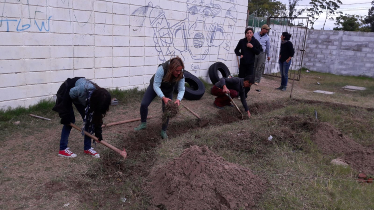 Jóvenes carpiendo y sacando pasto y tierra