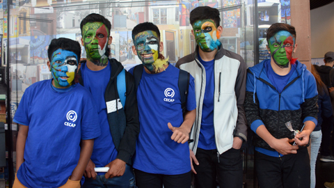 cuatro jóvenes remera azul pintados rostro con colores y plumas 